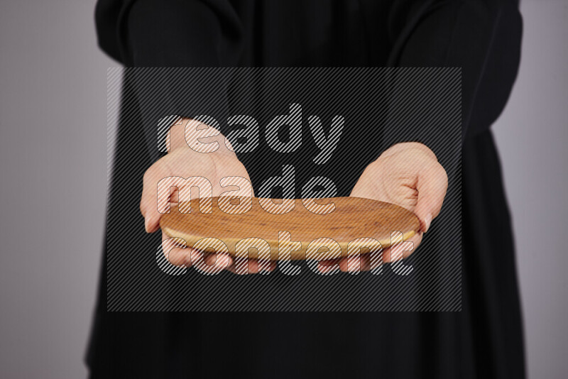 A woman in black abaya holding different wooden essentials in different positions