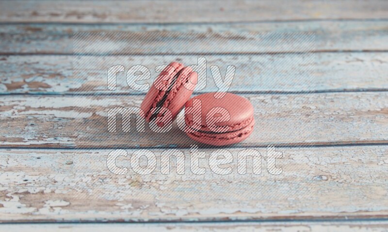 45º Shot of two Pink Raspberry macarons on light blue wooden background