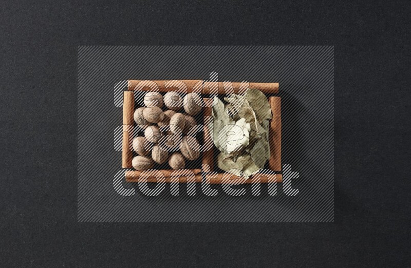 2 squares of cinnamon sticks full of nutmegs and bay laurel leaves on black flooring