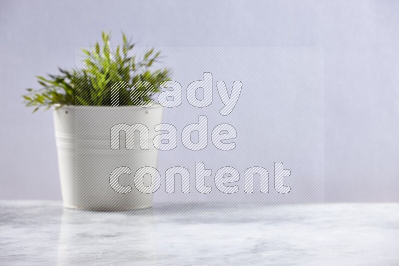 Artificial plant in white pot on grey marble background