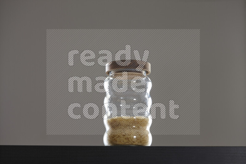 Basmati golden rice in a glass jar on black background