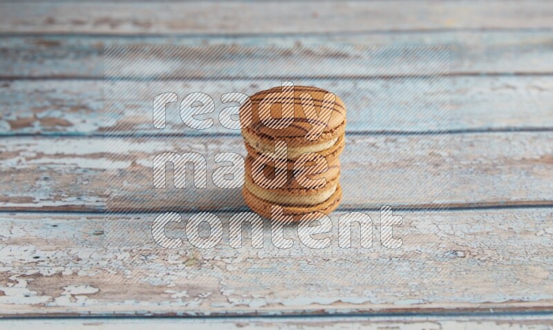 45º Shot of two light brown Almond Cream macarons on light blue wooden background