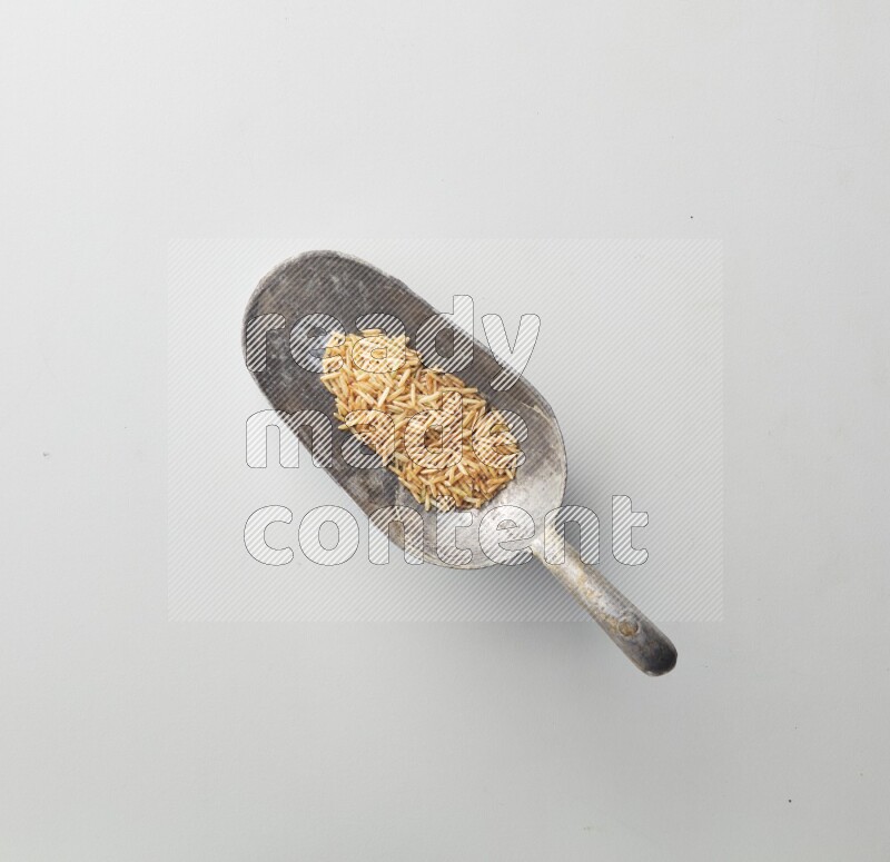 Top-view of a long grain brown rice, and shovel on white background