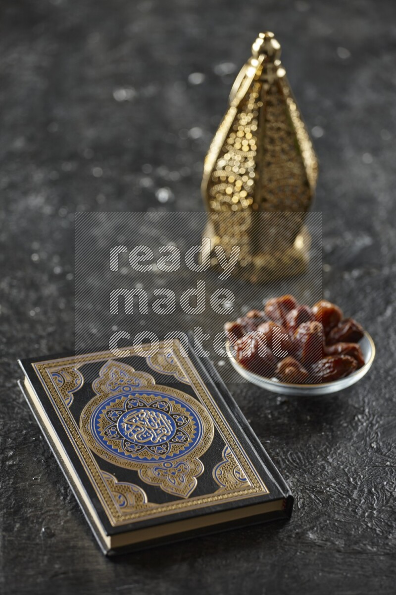 A golden lantern with different drinks, dates, nuts, prayer beads and quran on textured black background