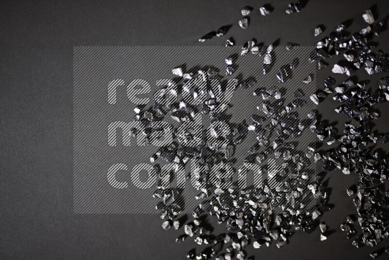 Black shimmering fragments of glass scattered on a black background