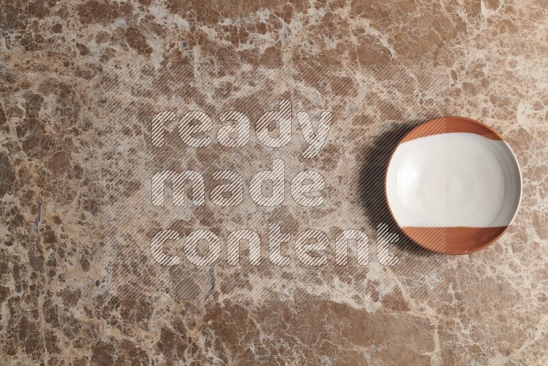 A decorative pottery plate on beige marble background