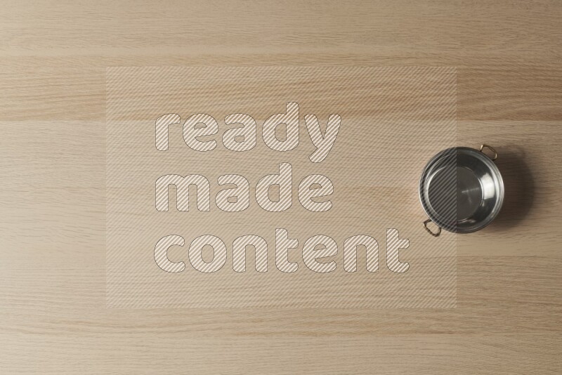 وعاء نحاسي صغير على خلفية خشبية فاتحة