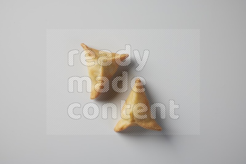 Two fried sambosa from a top angle on a white background