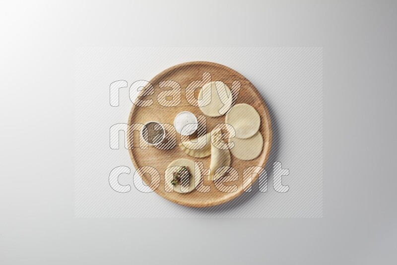 two closed sambosas and one open sambosa filled with meat while salt and black pepper aside in a wooden dish on a white background