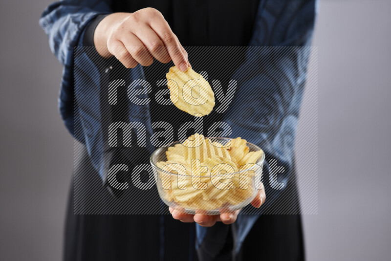 Woman in abaya holding different kinds of snacks in different positions
