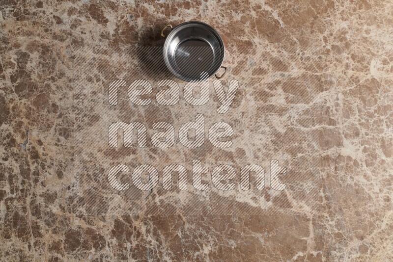 A small copper pot on beige marble background