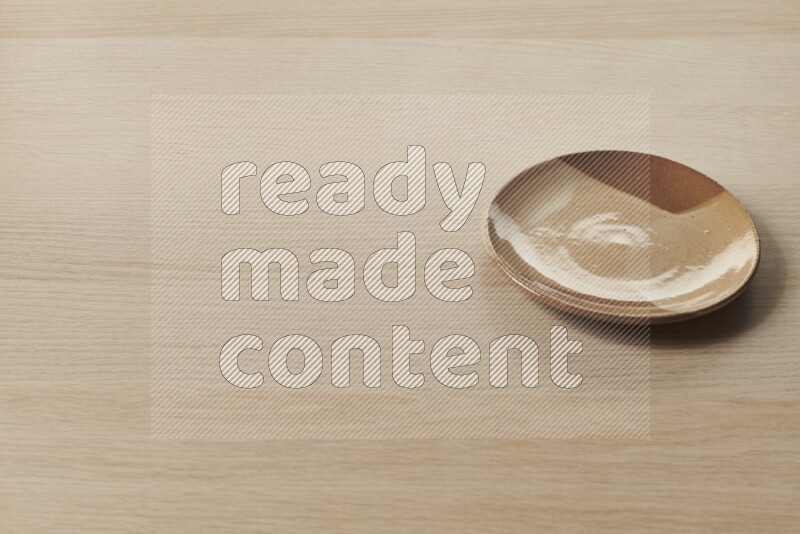 صحن فخاري متعدد الألوان على خلفية خشبية فاتحة