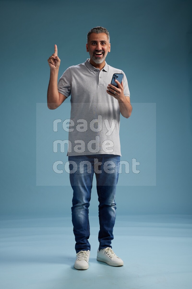 Man Standing texting on phone on blue background