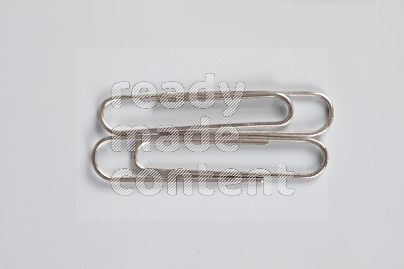 Silver paper clips isolated on a grey background