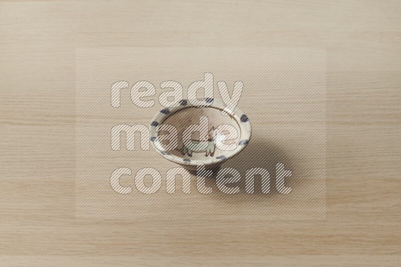 A decorative pottery bowl on light wooden background