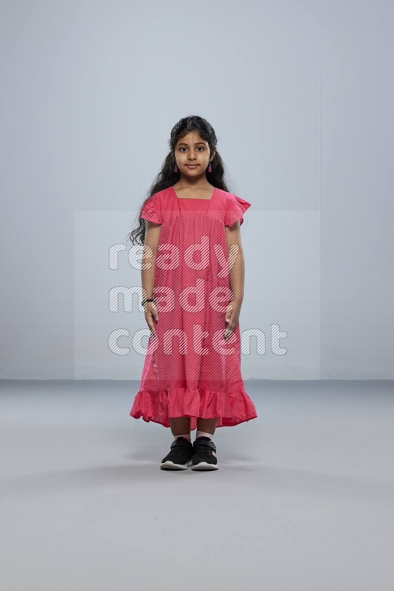 A girl standing interacting with the camera on gray background