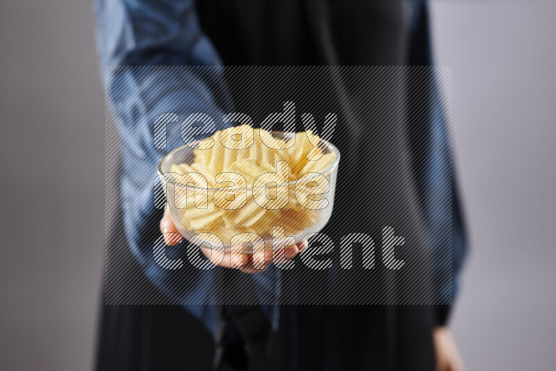Woman in abaya holding different kinds of snacks in different positions