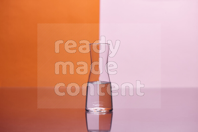 The image features a clear glassware filled with water, set against orange and rose background
