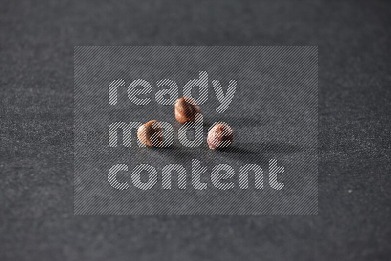 3 peeled hazelnuts on a black background in different angles