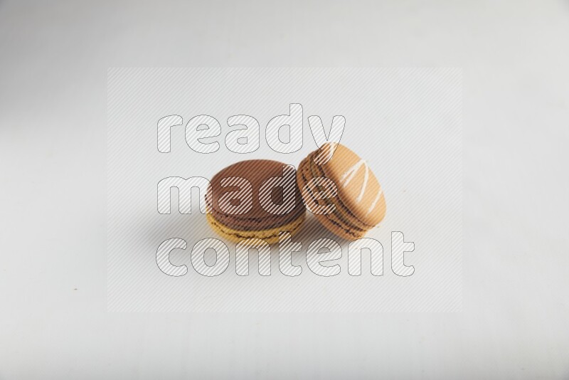 45º Shot of of two assorted Brown Irish Cream, and Yellow, and Brown Chai Latte macarons on white background