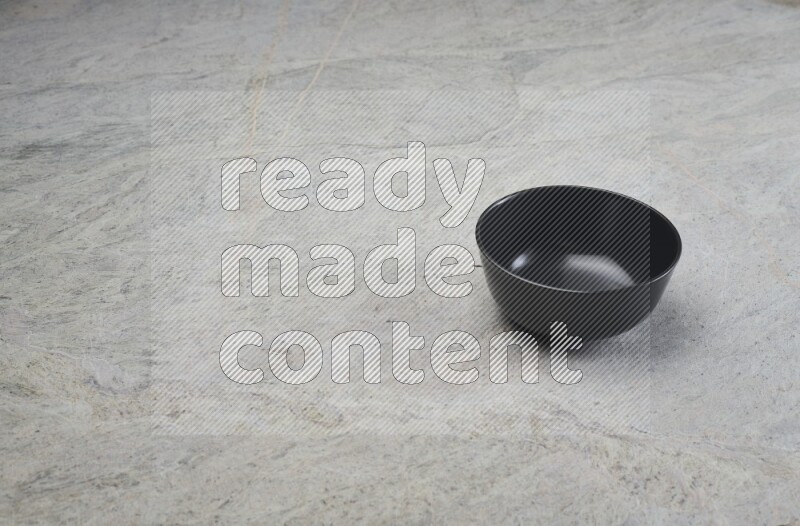 A black ceramic bowl on grey marble background