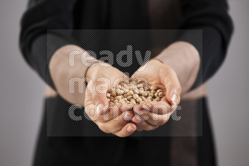 Woman in abaya holding different kinds of legumes in different positions