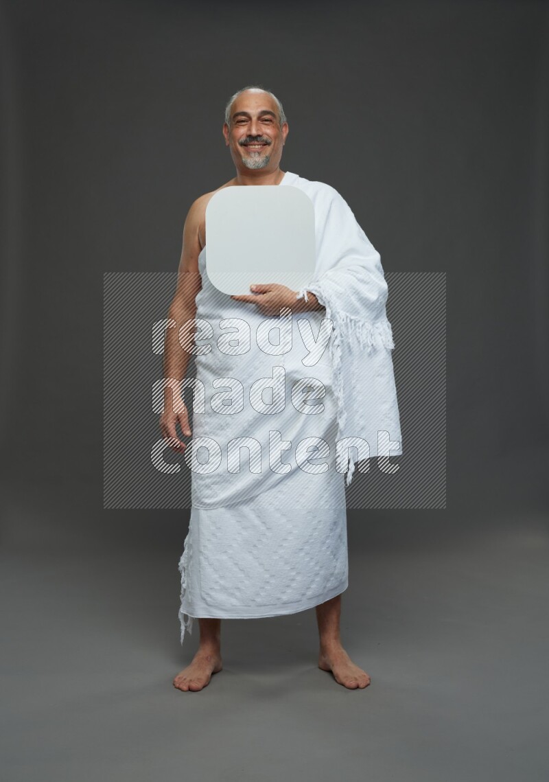 A man wearing Ehram Standing holding social media sign on gray background