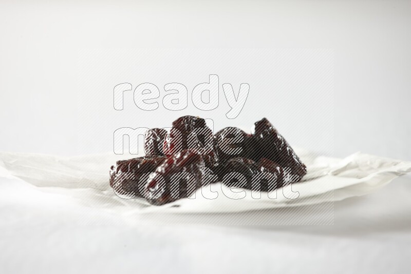 Dried plums on a crumpled piece of paper on a white background in different angles