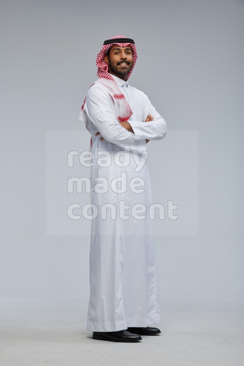 Saudi man Wearing Thob and shomag standing with crossed arms on Gray background