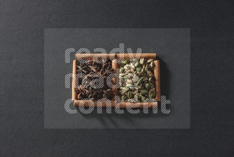 2 squares of cinnamon sticks full of cardamom and star anise on black flooring