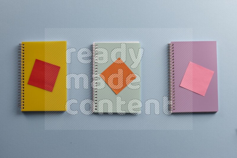 Multicolored notebooks with different school supplies on blue background