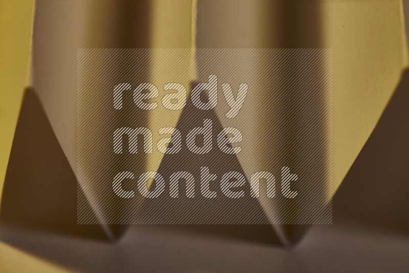 A close-up abstract image showing sharp geometric paper folds in warm gradients