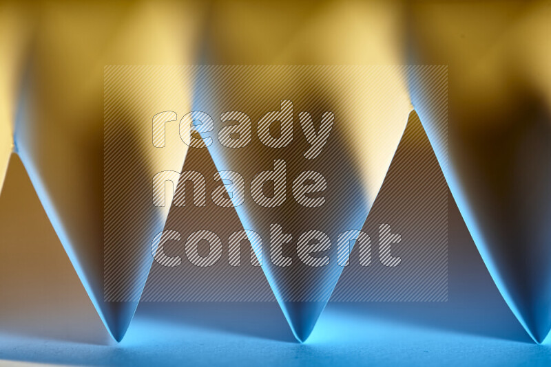 A close-up abstract image showing sharp geometric paper folds in blue gradients and warm tones