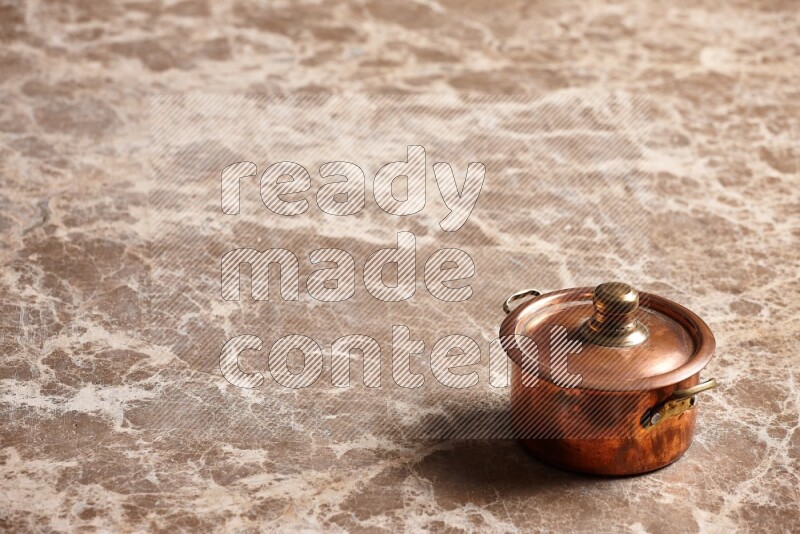 A small copper pot on beige marble background