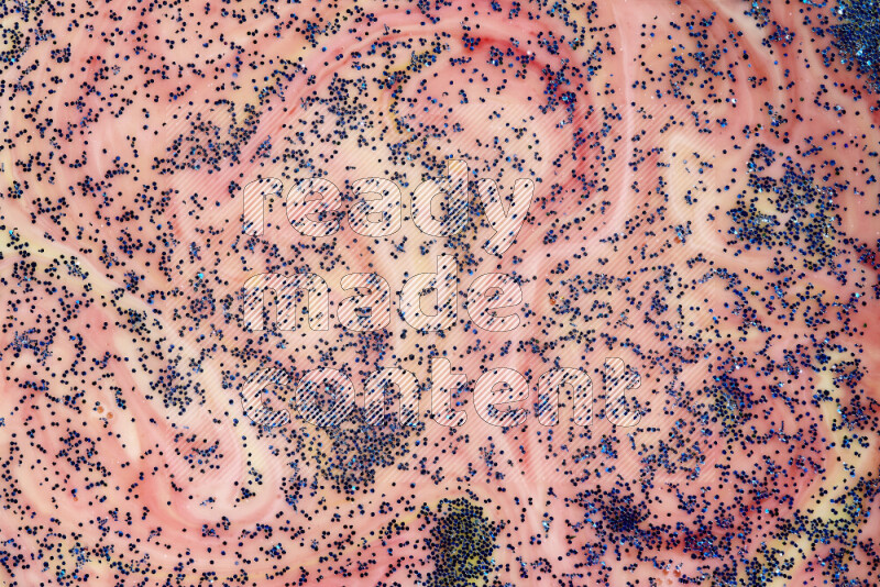 A close-up of sparkling blue glitter scattered on swirling yellow and red background