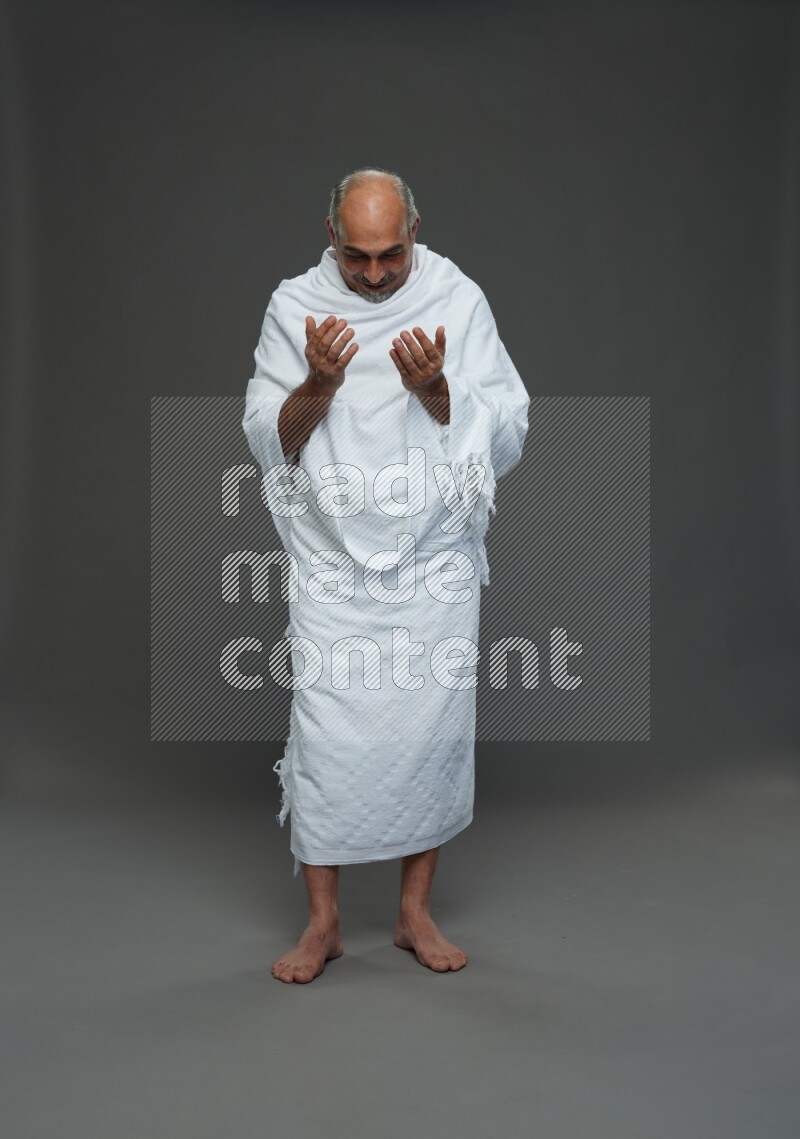A man wearing Ehram Standing dua'a on gray background