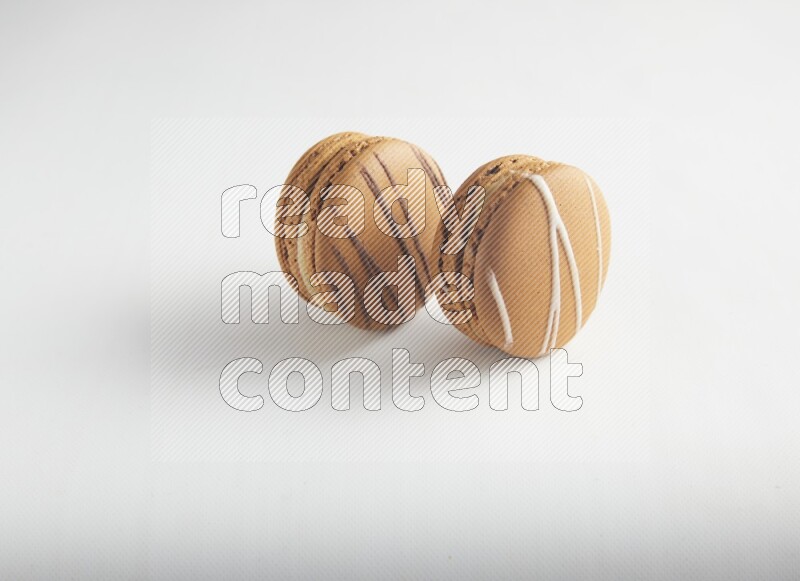 45º Shot of of two assorted Brown Irish Cream, and light brown  Almond Cream macarons on white background