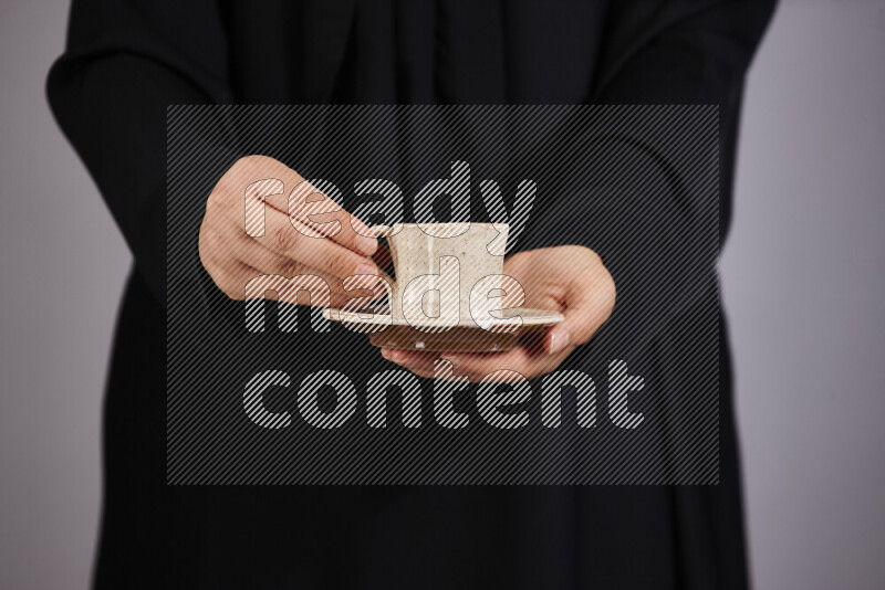 A woman in black abaya holding different pottery essentials in different positions