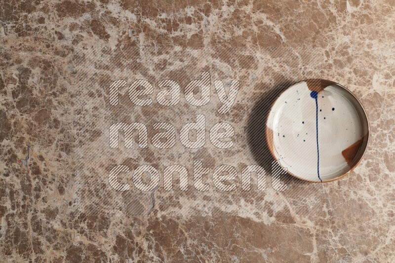 A multicolored pottery plate on beige marble background
