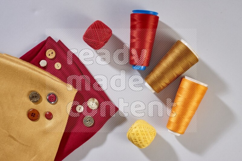 Multicolored fabrics with sewing supplies on grey background