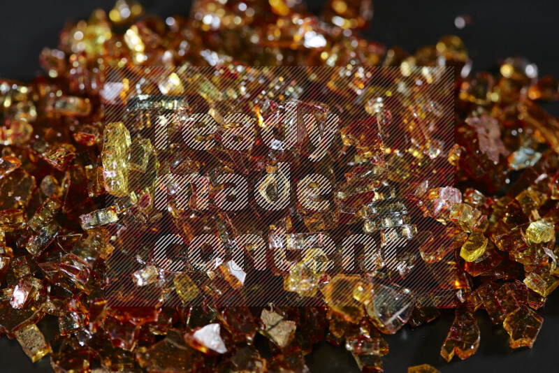 Transparent orange fragments of glass scattered on a black background
