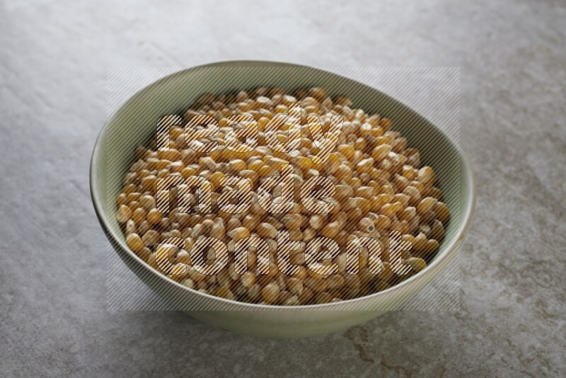 corn kernel in a green ceramic bowl on a grey textured countertop
