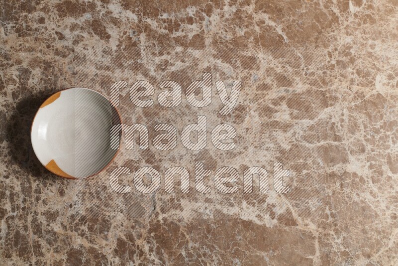A multicolored pottery bowl on beige marble background