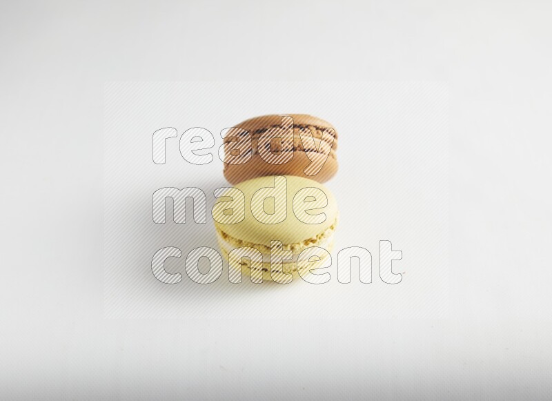 45º Shot of of two assorted Brown Irish Cream, and Yellow Lime macarons on white background