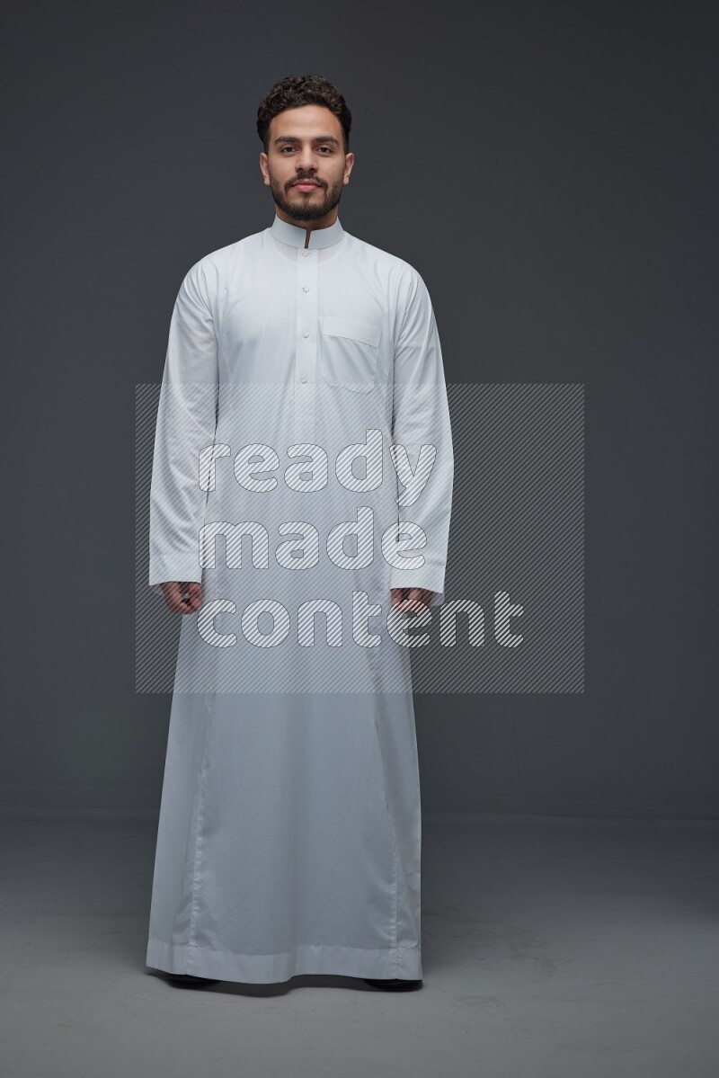 A Saudi man wearing Thobe standing and making different poses eye level on a gray background