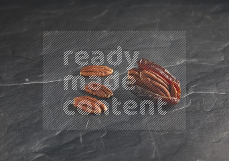 pecan stuffed madjoul date on a black textured background