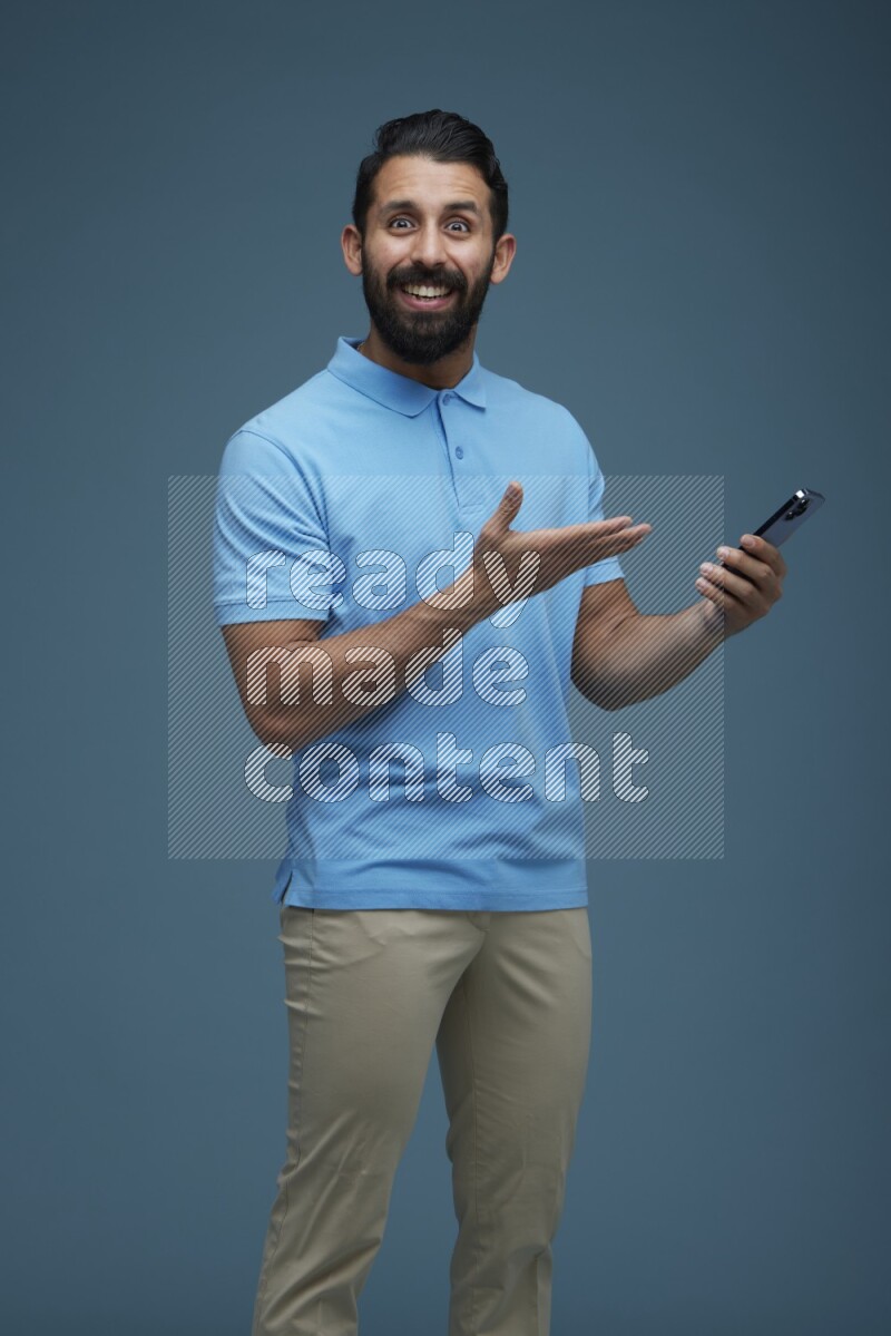 Man posing with a phone in a blue background wearing a Blue shirt