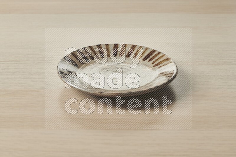 A multicolored pottery plate on light wooden background