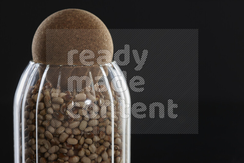 Black-eyed peas in a glass jar on black background