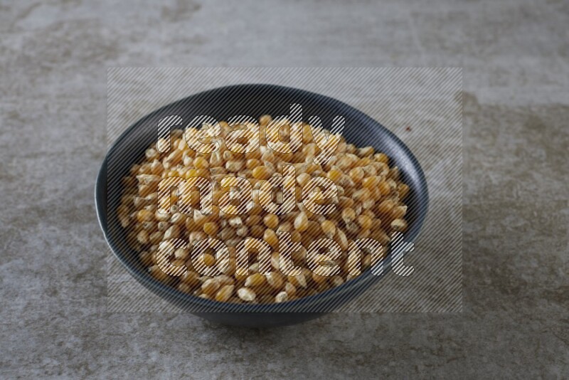 corn kernel in a black ceramic bowl on a grey textured countertop